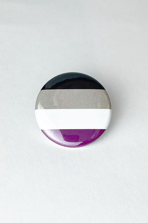 A pinback button featuring the colors of the Asexual Pride flag. 