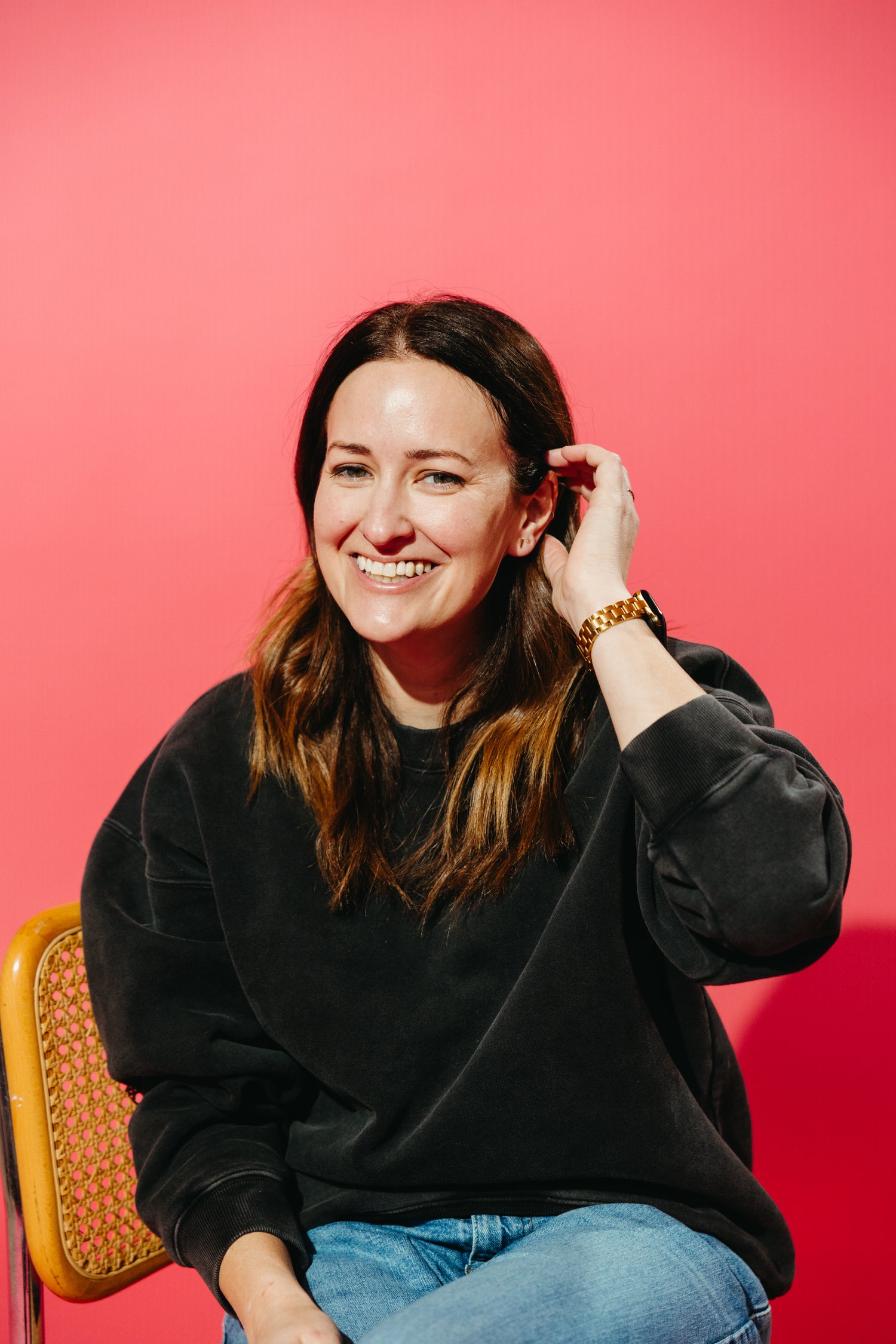 Co-owner Brittany sitting in a chair against a pink backdrop