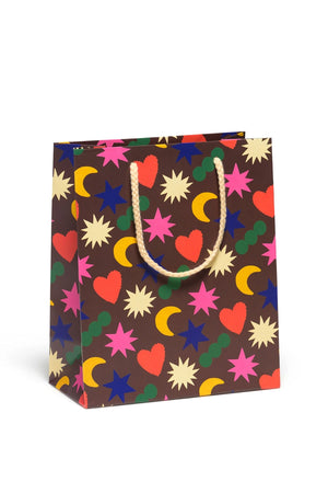 Brown Gift bag with cream color rope handle. Bag features all over print of yellow moons, red hearts, green dots, and white, blue, and pink stars.