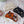 Load image into Gallery viewer, Photograph of three hair claw clips in the shape of a cats face. There is a white, black, and tortoise version of the clips laid out on a floral plate.