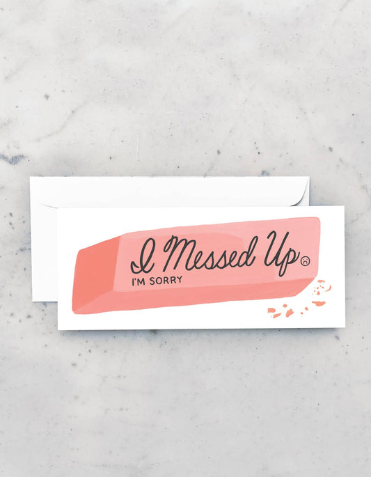 White card with white envelope on a gray marble backdrop. The card features a pink eraser  that says I Messed Up, I'm Sorry.