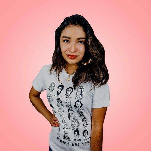 An olive-skinned woman wearing a white tee shirt with illustrated depiction of historically significant female artists.