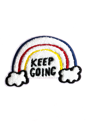 A white chenille patch with embroidered red, blue, and yellow lines forming a rainbow emerging out of clouds. The black embroidered text reads "Keep Going."