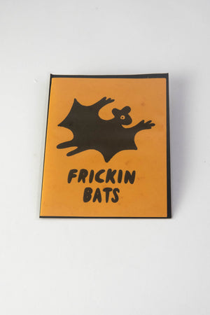 An orange greeting card with an illustrated black bat and text that reads "Frickin bats." White background.