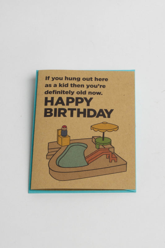 A kraft-paper greeting card with an illustration of a Fisher Price pool playset. The text reads "If you hung out here as a kid then you're definitely old now. Happy Birthday!"