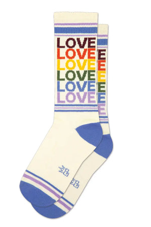 Vintage white mid-calf crew socks. The socks have a light blue heel and toe with a thin blue and purple stripe across the toe and across the top of the socks. The socks say Love in a repeating pattern in vintage looking colors of Burgundy, orange, yellow, sage green, light blue, and lilac purple. White background.