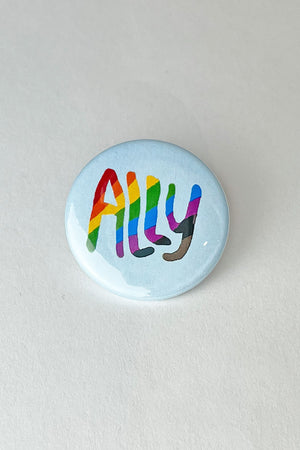 A light blue pinback button with the word "ALLY" in rainbow colored text.