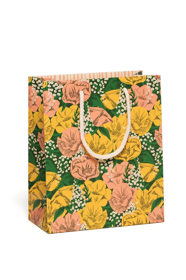 Gift bag with white rope handles. Gift bag design is of pink and yellow flowers in a bed of green leaves with baby's breath flowers scattered throughout the design.