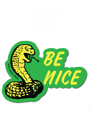 Green die cut sticker of a yellow cobra snake. Next to the snake the sticker says Be Nice in yellow text. White background.