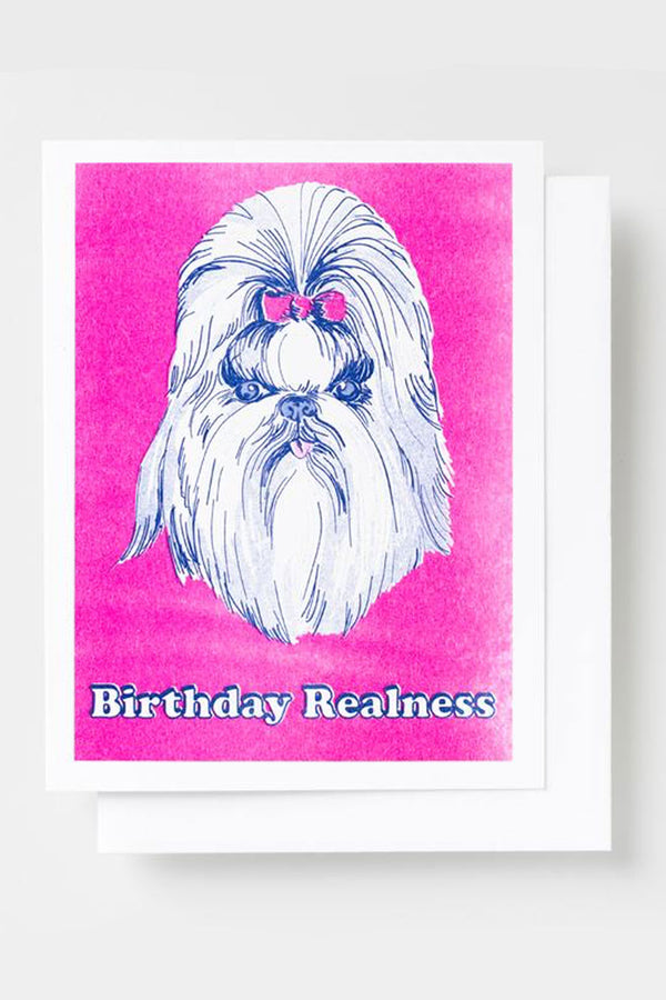 Greeting card featuring a white dog with its hair in a bow. Under the dog the card says Birthday Realness.