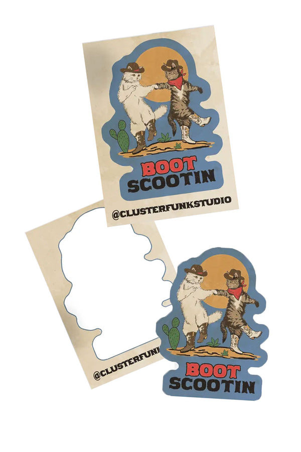 Blue die cut sticker featuring illustration of two cats wearing cowboy boots and hats, dancing in the desert. Below that the sticker says Boot scootin in wester font. White background.