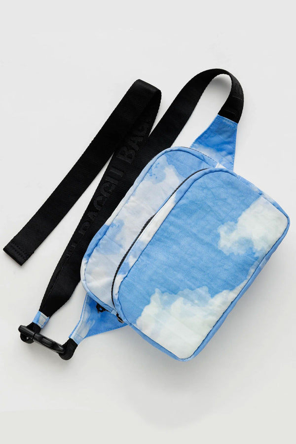 A nylon fanny pack featuring black straps and realistic clouds against a blue sky printed all over. White background.