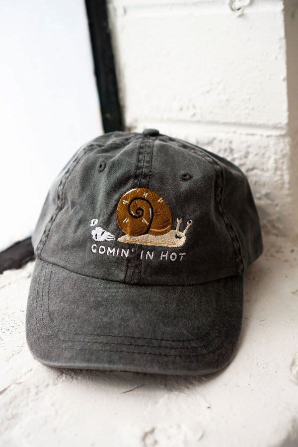 Gray dad hat with embroidered Snail with dust behind it. Below the snail the hat says Comin' in hot. 