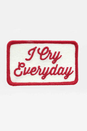 White rectangle patch with rounded edges embroidered in red thread. The patch says I Cry Everyday in red font. White background.