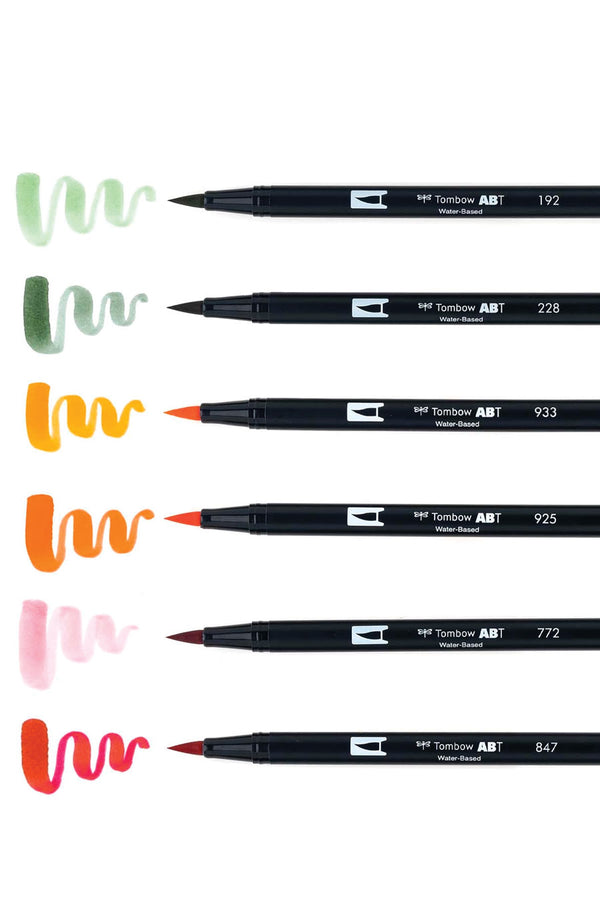 Set of 6 colors. Dual Brush Pens feature flexible brush tip and fine tip in one marker. Colors include Crimson, Dusty Rose, Scarlet, Orange, Gray Green, and Asparagus. The markers are laid out next to an example of the brush end of the marker.