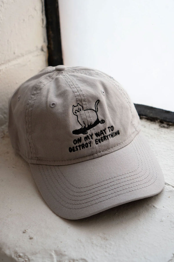 Gray 6 panel hat with embroidered design of a cat on a skateboard. Below the cat the hat says On my way to destroy everything.