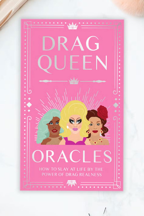 Pink box that features three drag Queen on the front. the box says Drag Queen Oracles; How to Slay at life by the power of drag realness.