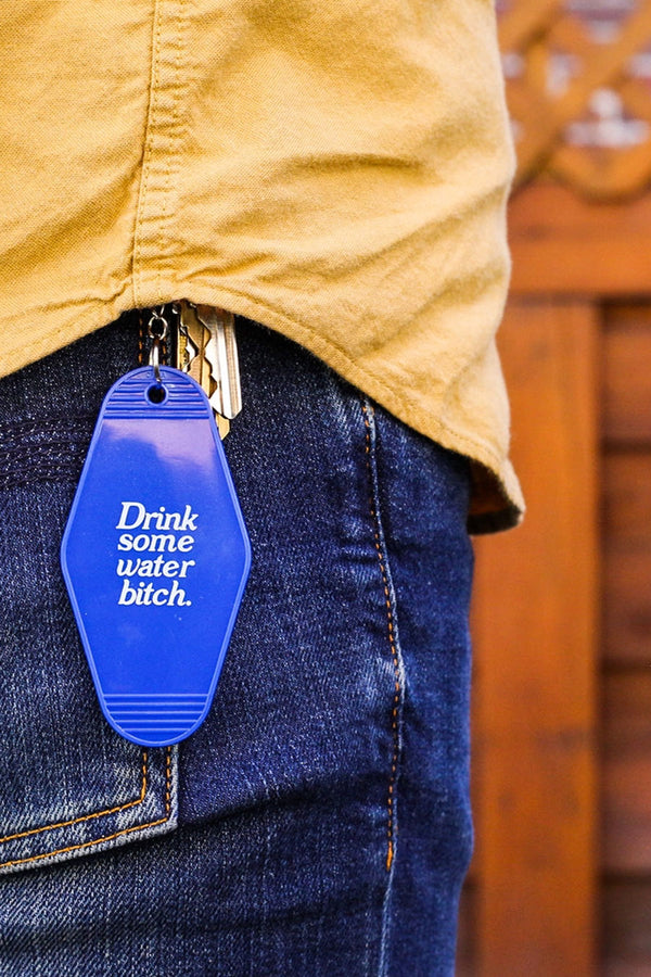 Blue vintage motel style keychain that says Drink some water bitch in white text.