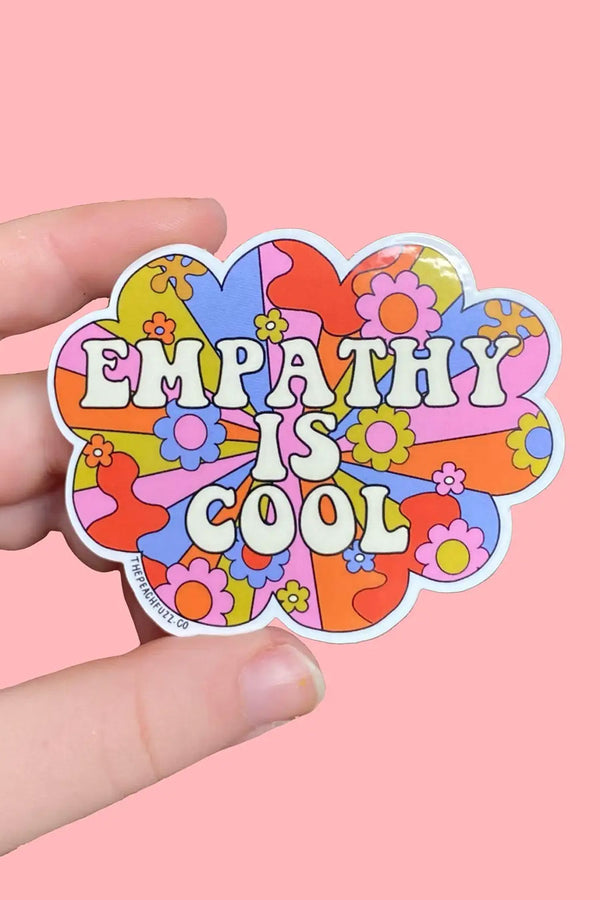 Die cut sticker in a cloud shape. Sticker features a starburst of color with flowers and and squiggly shapes. On Top of the Starbust the sticker says Empathy is Cool.