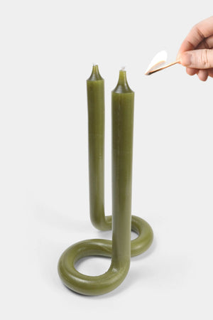 Someone lighting an Olive green twist candle with two wicks.