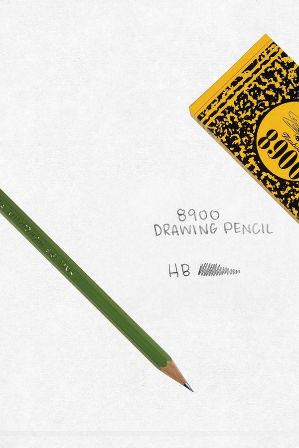 Wooden Green HB Tombow graphite pencil next to an example of the pencil markings and a portion of the pencil box. The box is yellow with black speckles and says Tombow 8900. White background.