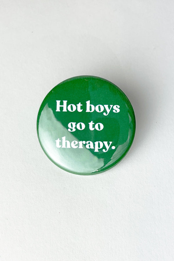A green pinback button with white text that reads "hot boys go to therapy."