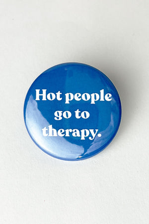 A blue pinback button with white text that reads "hot people go to therapy."
