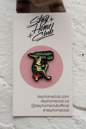 Enamel Pin of a frog sitting on a toadstool holding a leaf as a umbrella.