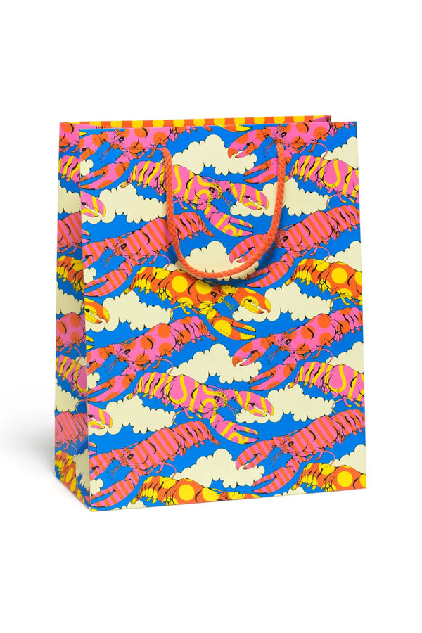 Blue gift bag with red rope handles. The bag is printed with white clouds, and pink kand orange lobsters printed all over. Some lobsters have stripes, yellow dots, or yellow swirls on them.
