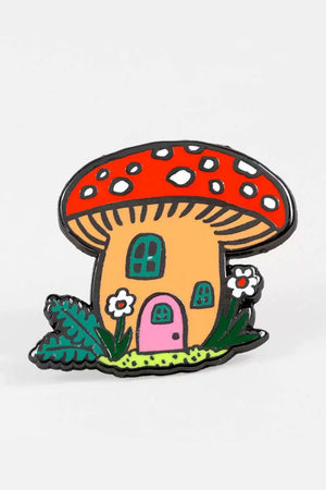 Enamel pin of a mushroom with a red cap that is a cottage. The cottage has a pink door, windows, and surrounded by daisies.