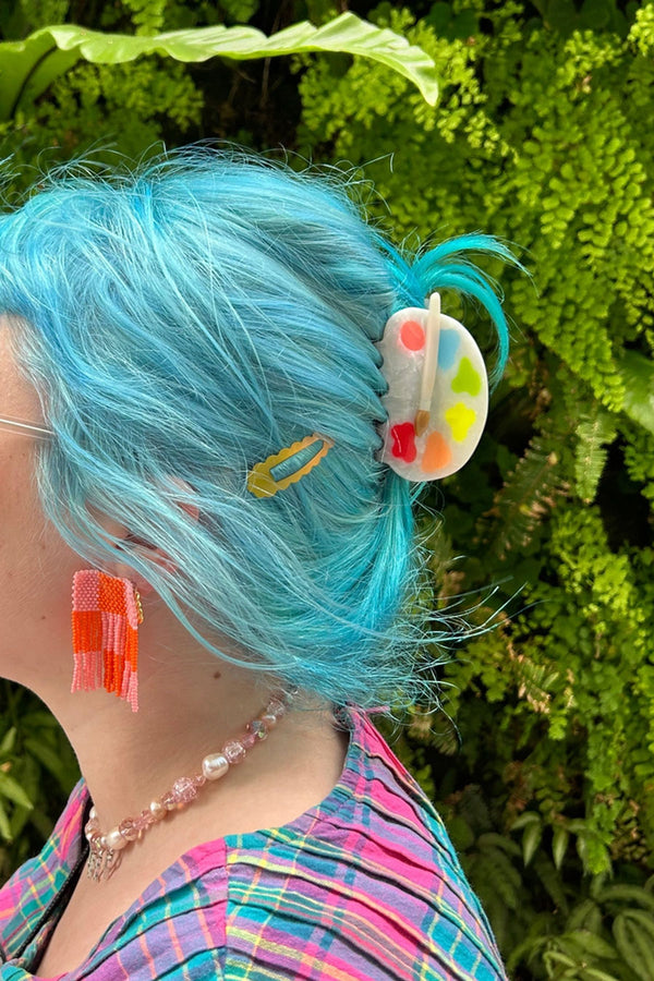 Hair claw clip designed like a painters palette. Clip features pink, blue, green, yellow, orange, and red paint blobs and a paint brush laying across the top.