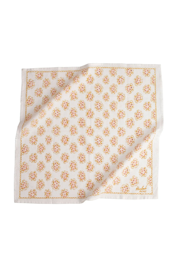 White bandana featuring dainty clusters of pink flowers printed all over with a scallop line work border. White background.