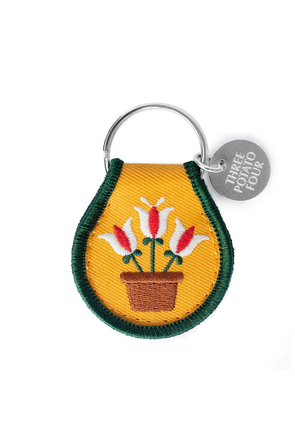 Yellow embroidered Keychain tag with green edge. Features white and red tulips in a pot.