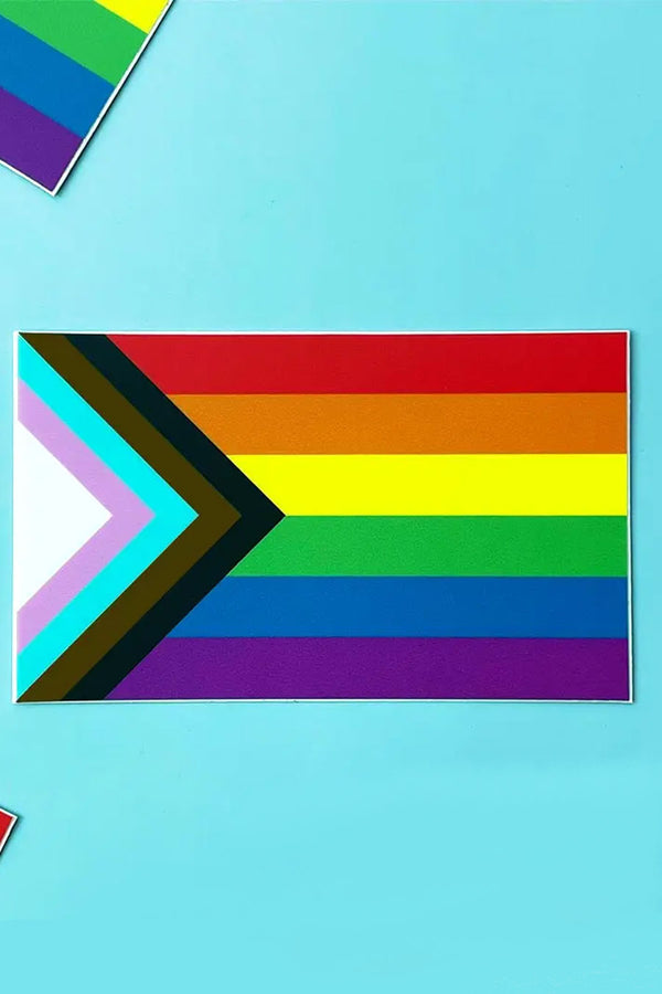 Progress Pride Flag sticker against an aqua blue background. The Progress Pride Flag includes a black, brown, blue, pink and white stripe layered on top of the rainbow colors.