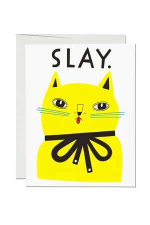 White card of a yellow cat with a black ribbon around its neck. Above the cat the card says SLAY. White background.