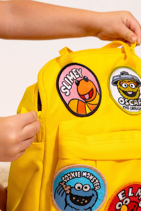 Embroidered circle patch of Slimey the worm from Sesame Street on a yellow backpack.