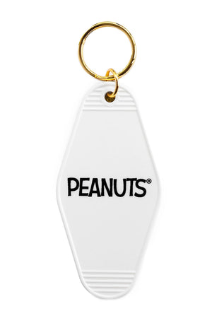 The back of a vintage Motel style keychain. The keychain says Peanuts and has gold hardware. White background.
