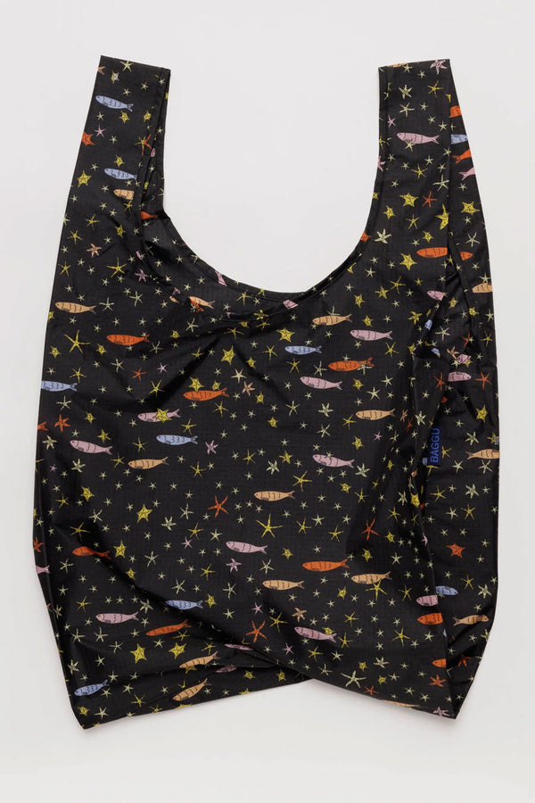 Black reusable tote bag with multicolor fish and stars all over it. White background.
