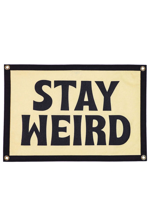 Ivory camp flag with black border and four grommets, one on each corner. The flag says Stay Weird in bold black lettering. White background.