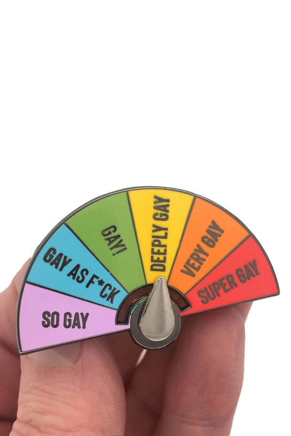 Someone holding an Enamel pin with a movable dial hand. You can set the dial on one of 6 levels. So Gay, Gay as F*ck, Gay! Deeply Gay, Very Gay, and Super Gay. Each level is a color of the rainbow.