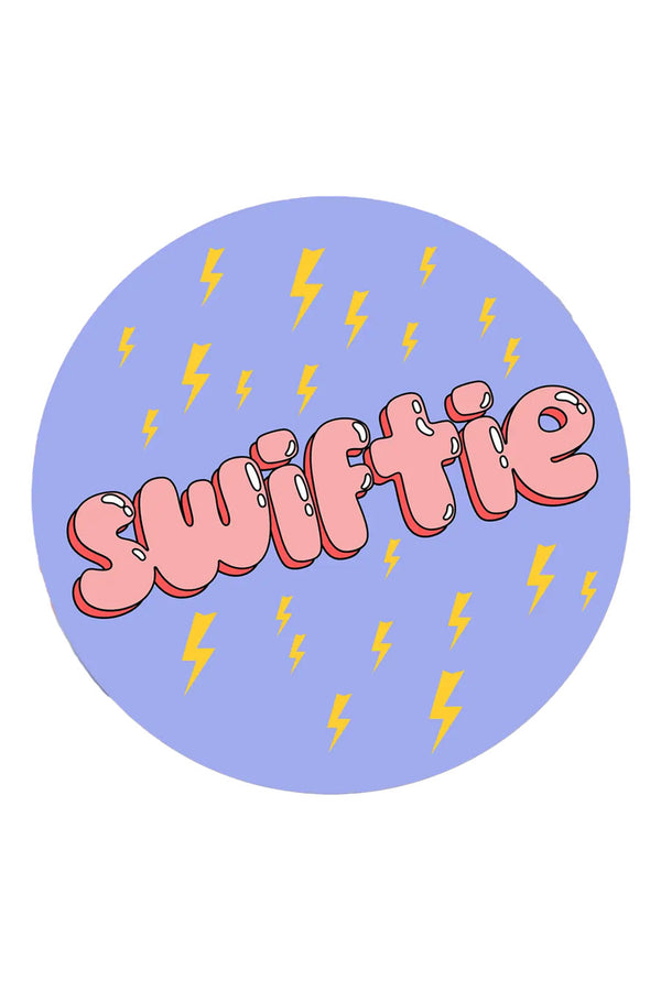 Blue die cut circle sticker with yellow lightning bolts all over. The sticker says Swiftie in pink bubble lettering. 