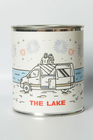 Candle in a Tin. Label says The Lake and features a couple sitting on top of an RV looking across the lake with fireworks in the sky.