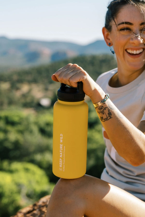 A person holding an insulated 32oz Water Bottle with Handle Clip in Tucson Sun color.