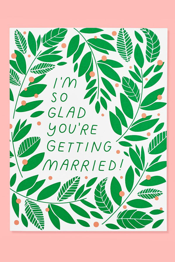 White greeting card covered in illustrated vines and pink dots. The card says I'm so glad you're getting married! Pink background.
