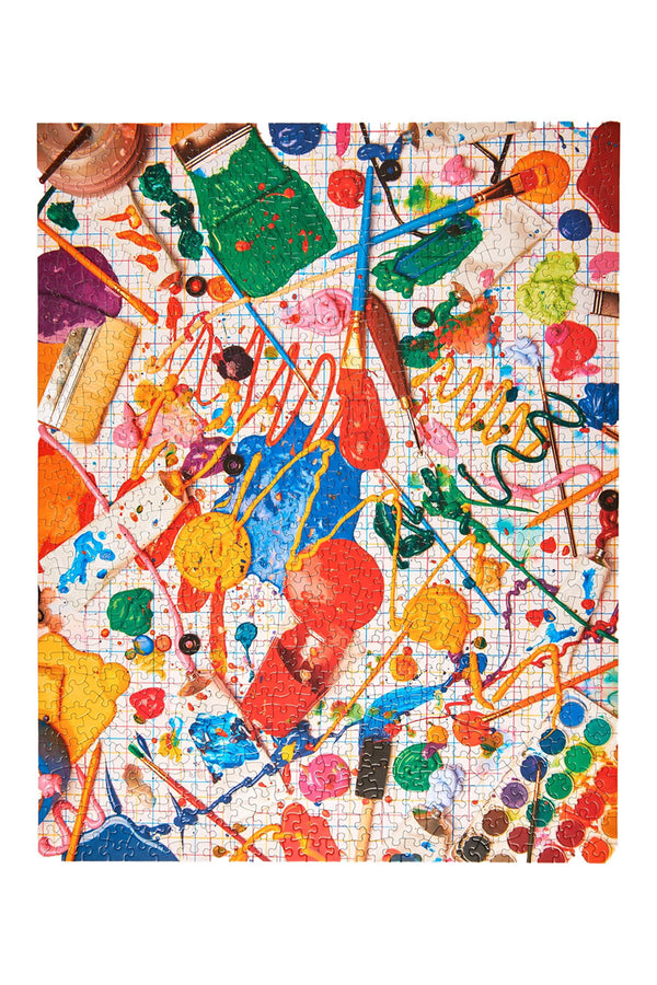 1000 piece puzzle of splattered paint and art supplies. White background.