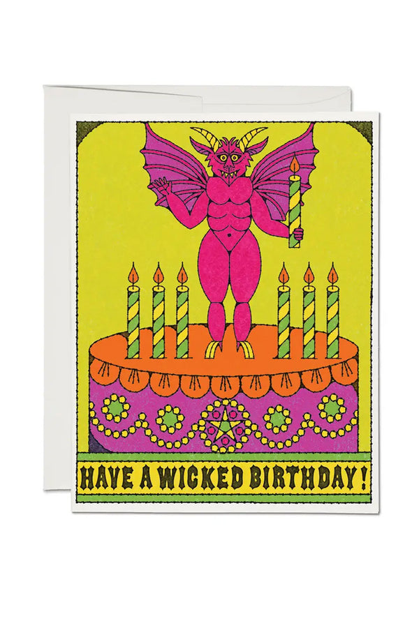 White birthday card featuring an illustration of a birthday cake with a winged devil on top, holding a candle. Below the illustration the card says Have a Wicked Birthday. White background.