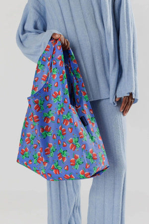 Person holding a Blue reusable shopping bag featuring Starwberries printed all over it.