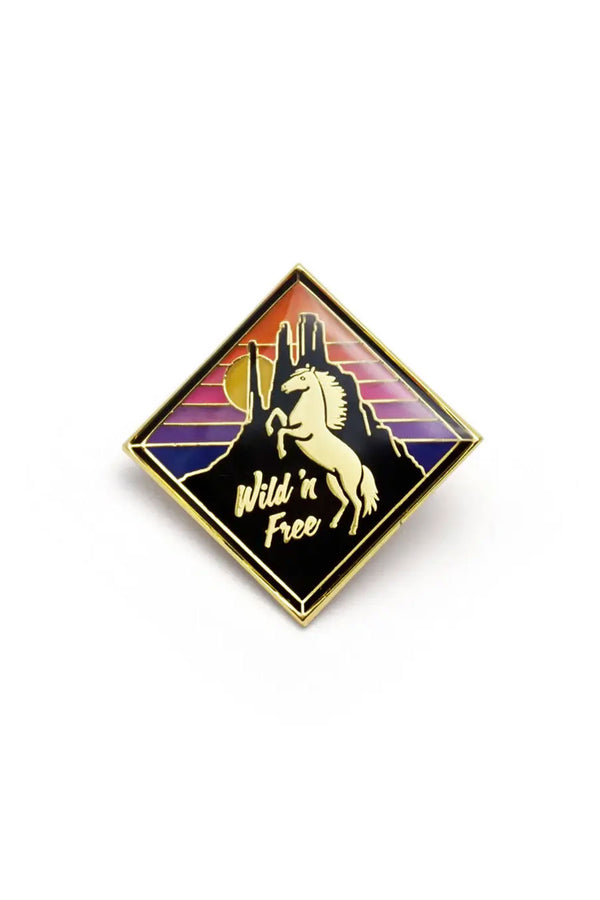 Diamond shape enamel pin of a white stallion rearing up infront of a mountain sillhouette. the sky is a blue, purple, pink, and orange stripes. White background.