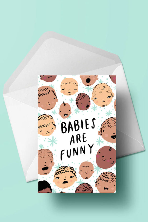 White greeting card against a teal background. The card features illustrations of babies faces all over it. In the middle the card says Babies are Funny.