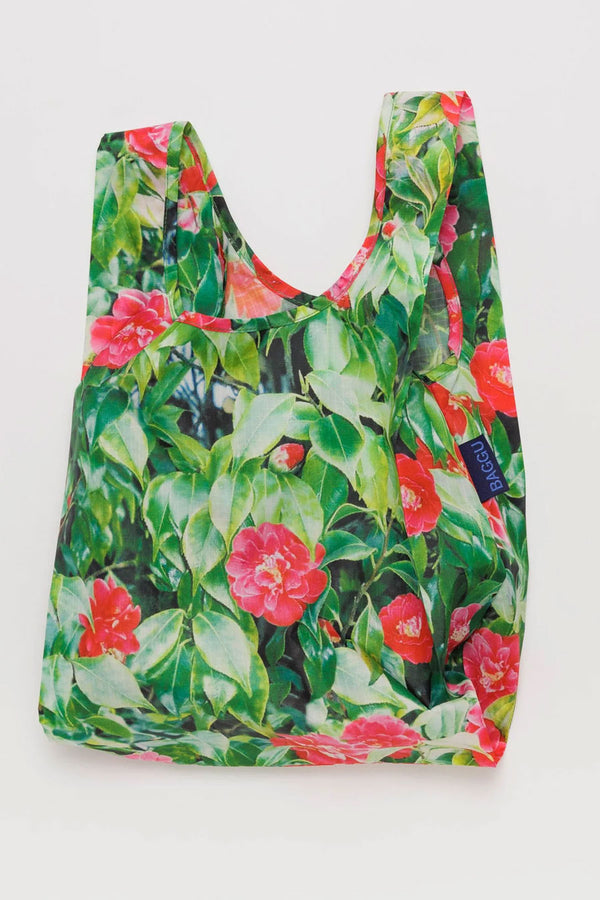 Reusable shopping bag covered with a photo of red flowers and leaves all over it. White background.